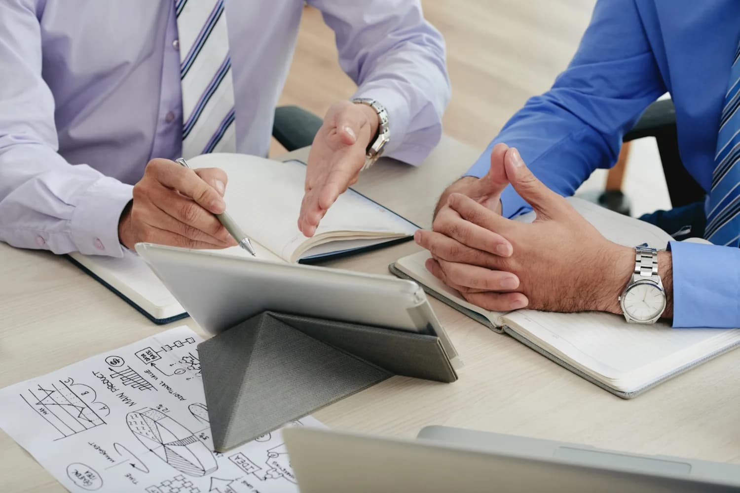Two colleagues discussing a plan over notes and a tablet